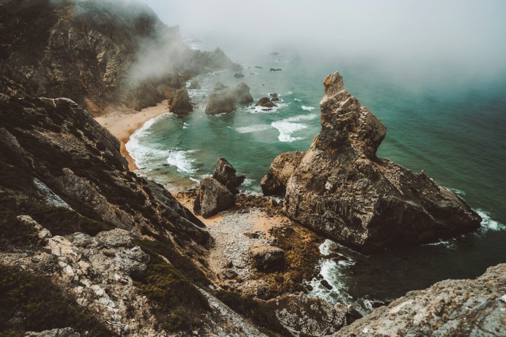 Sentra, Portugal. Moody foggy weather at Praia da Ursa beach on morning. Rough Atlantic Ocean